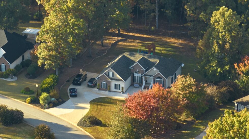 Aerial view of new family house between yellow trees in South Carolina suburban area in fall season. Real estate development in american suburbs. SSUCv3H4sIAAAAAAAACoxTTY+bMBC9V+p/iHxuJGMDxvsjqt5XPQxgghUHI9tsW63y3zsGnDjptuoNv/l4b+YN758/HQ6kBa878nJ4jy98a2MWHxwEbSeE6Zcdd2rqlcuRN8drmgOg85fqdbBOg8nBFkI3TnBRCE6LMRG+rkHiA4TFK59p8eMSgnI+2O6MME9dZjv1VQ60+rQmzaMN9iFT/wyAQJERdRDUCZU9UKU1vG7vQwqsQazAECF7103b0q5Ygrbmf6n8iqM59VH9N3Bnf2+yfXy/bfSkpu5XlHnNBnDKKNg29bqlkvMP3NNlHWhPgqXXNhvwzXZgYgLPOoGewcFD3ex0p6dThtgwrsanTp1dpuCiKsIYS0MRY+0MrYnODsikEj6C91jRJzx3Ai/NXjKqyYZ1rH3VpEer4rPgvJQlKyQtqGCsEhXJj2bU2GdVlDQus7HQq0h6s+P5nIq6oVzQilU3X26XFWOCF41k99jzkW05rG5kVp/uTVAULCRbD+9+HdH2i0YV/6GsYDzd8R/KKlllqj9WVlNW7uwPvxkm6v4fvxm62nAmWSnEzdzEThgXdck4vfv+TE5KUVIpOFZntDoOTIqWdrwd5HFQrTyWVSOPMAzsqIamalnRCqUoVl1/AwAA//8DAI0dFqSbBAAA
